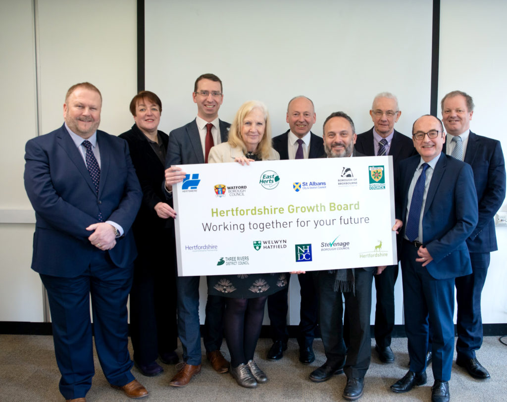 Members of Hertfordshire Growth Board together with placard of logos and message that reads: Working together for your future