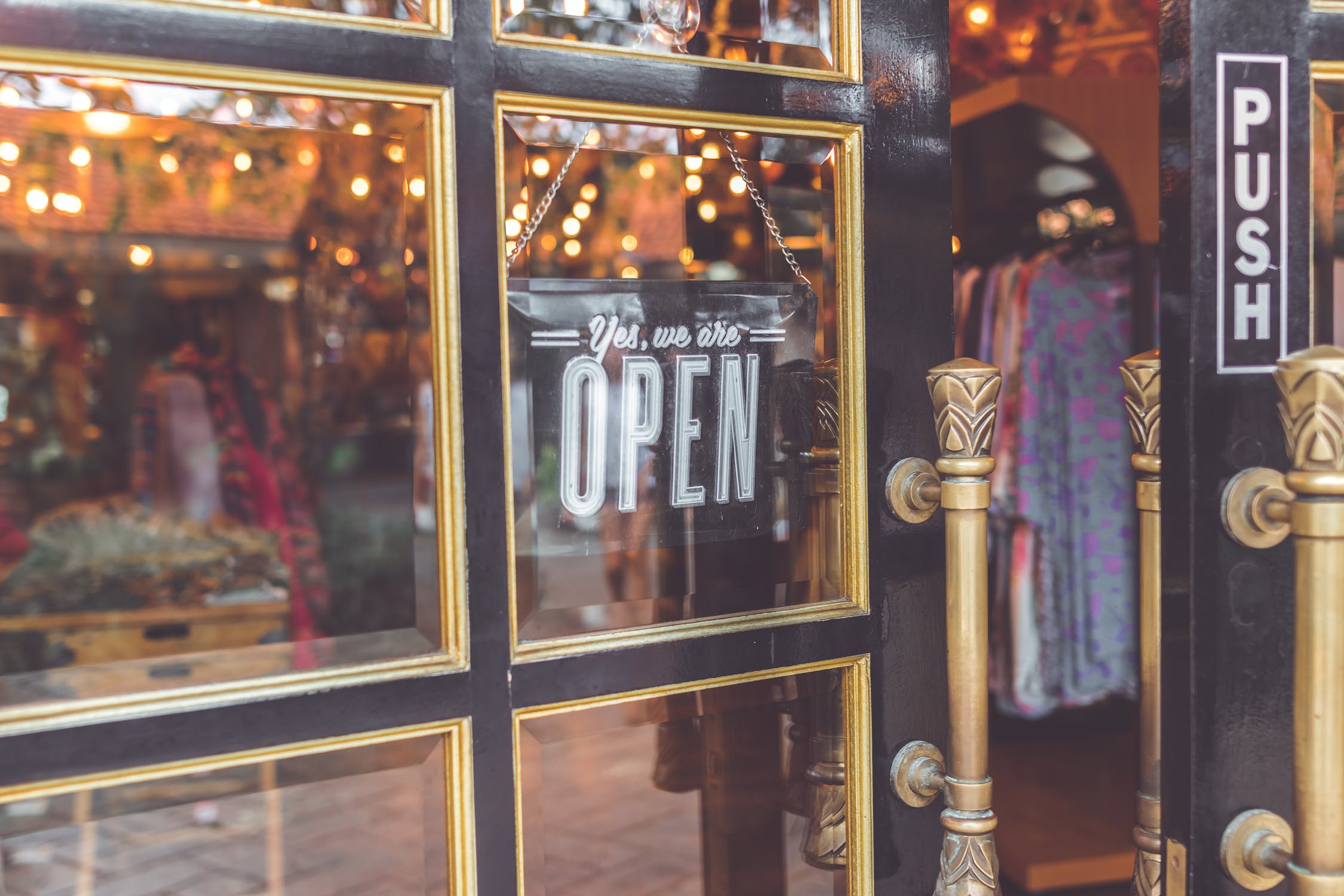 Close-up of shop door with yes we are open sign